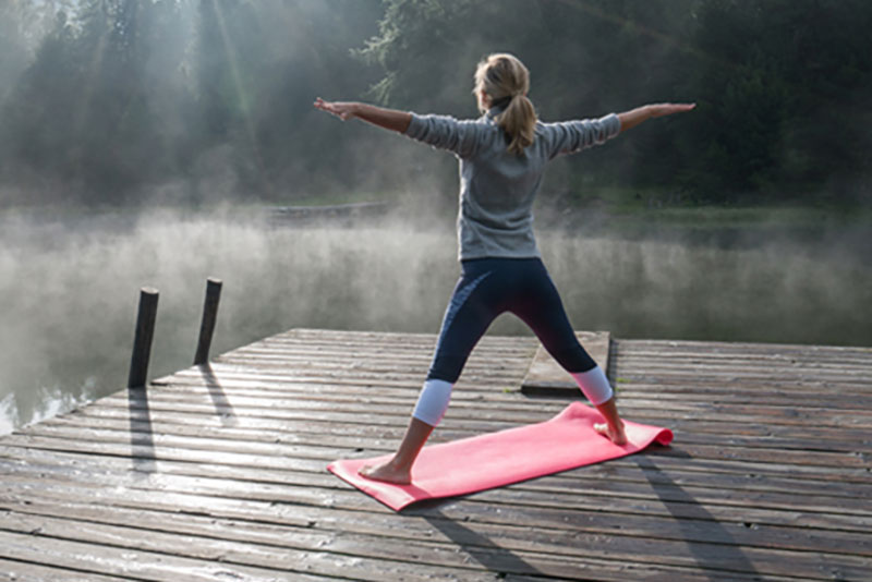 Woman in yoga pose on dock