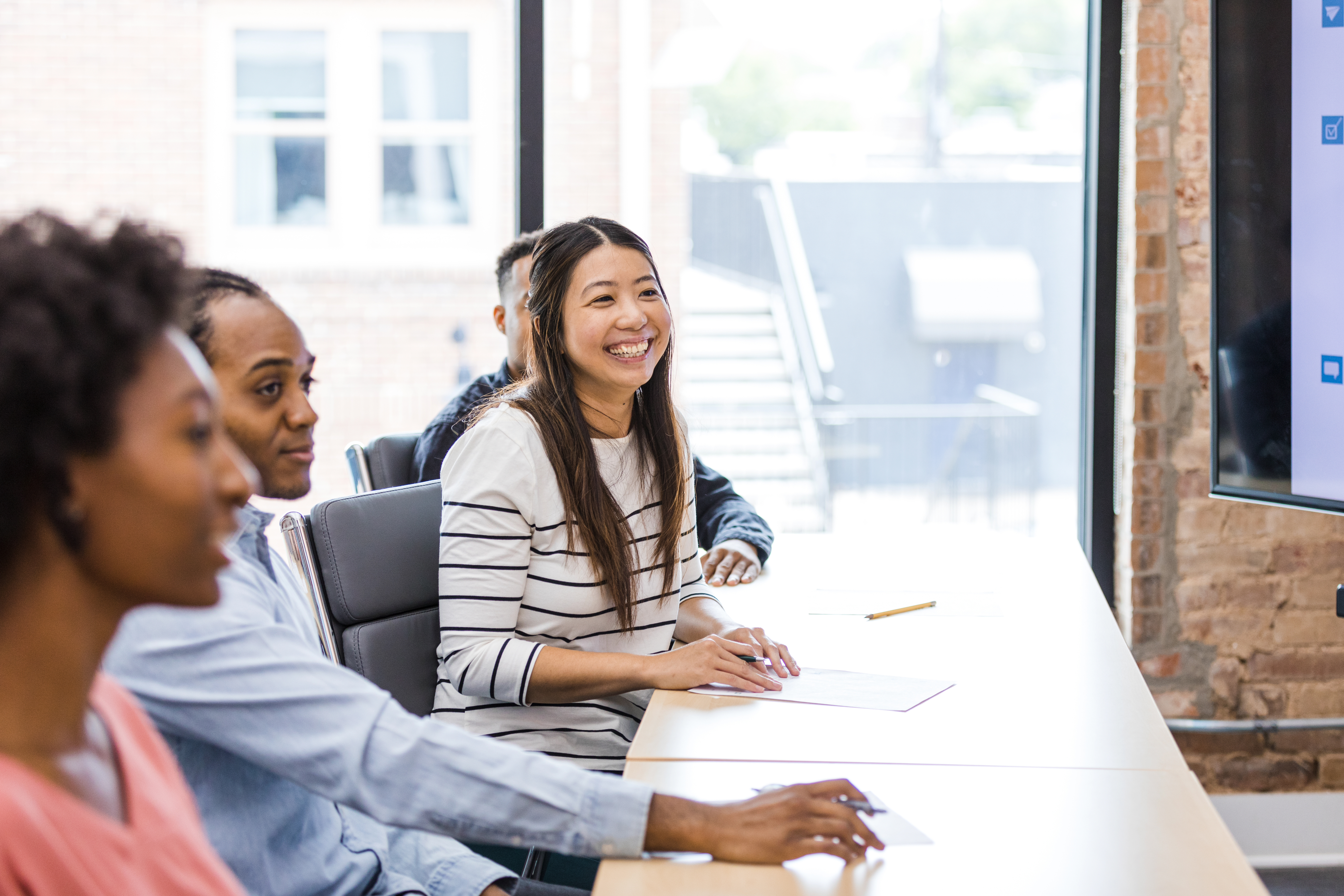 Woman working with others along a long desk